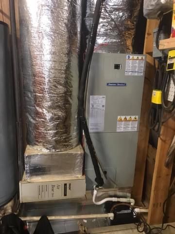 HVAC furnace and ductwork in a utility closet with exposed pipes and framing