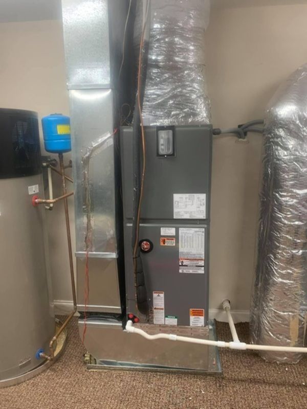 Basement HVAC unit with insulated ductwork, gray metal cabinet, and exposed utility pipes.