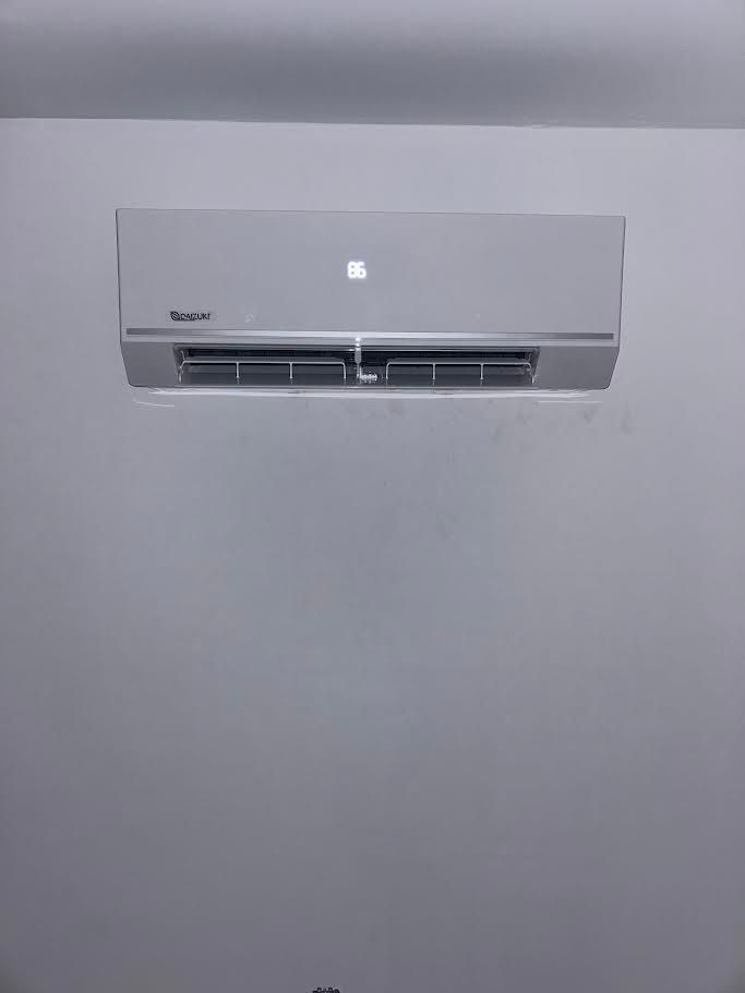 Wall-mounted white air conditioner on a plain light gray wall.