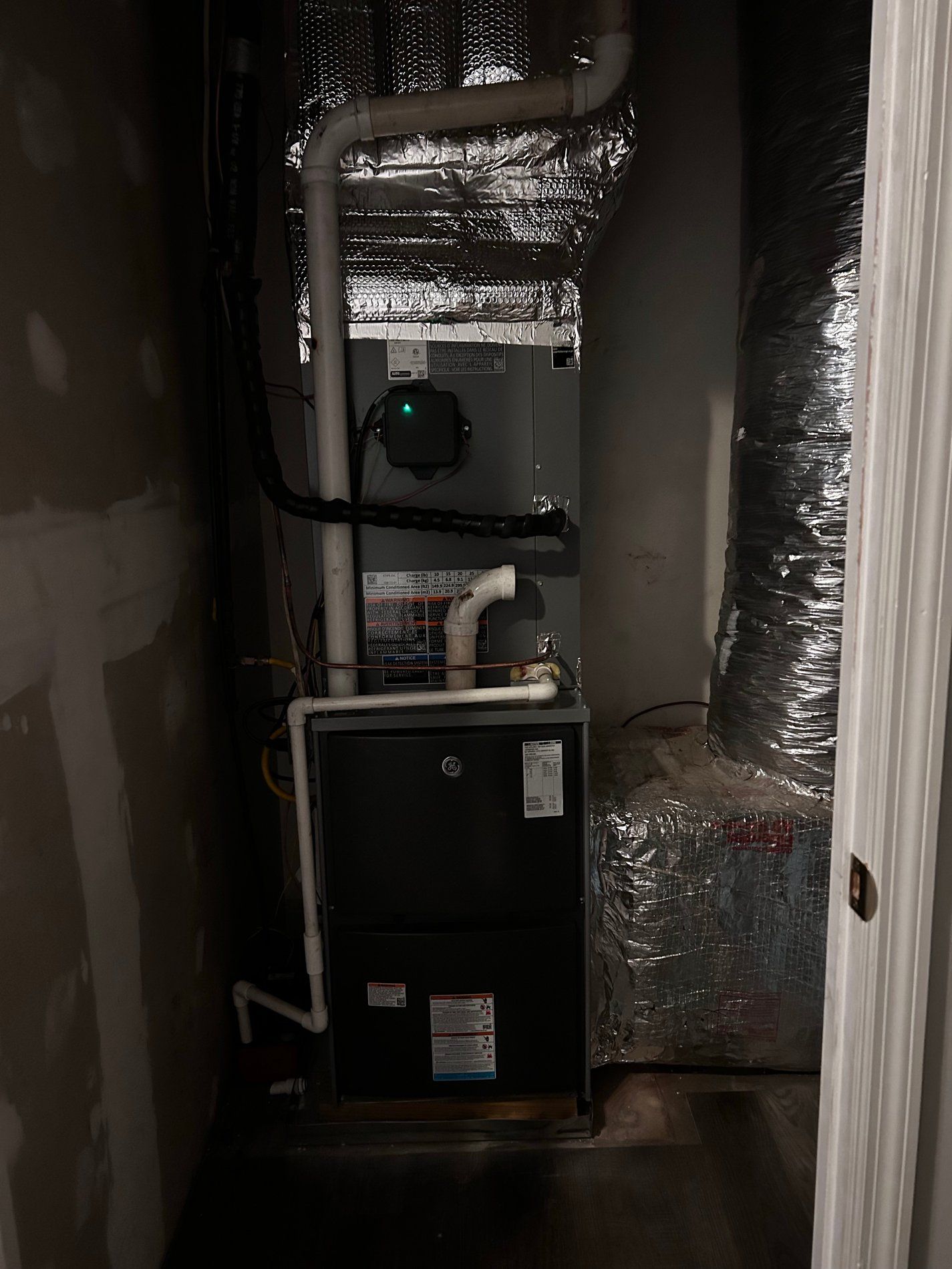 Utility closet with a furnace and HVAC ductwork wrapped in silver insulation foil.