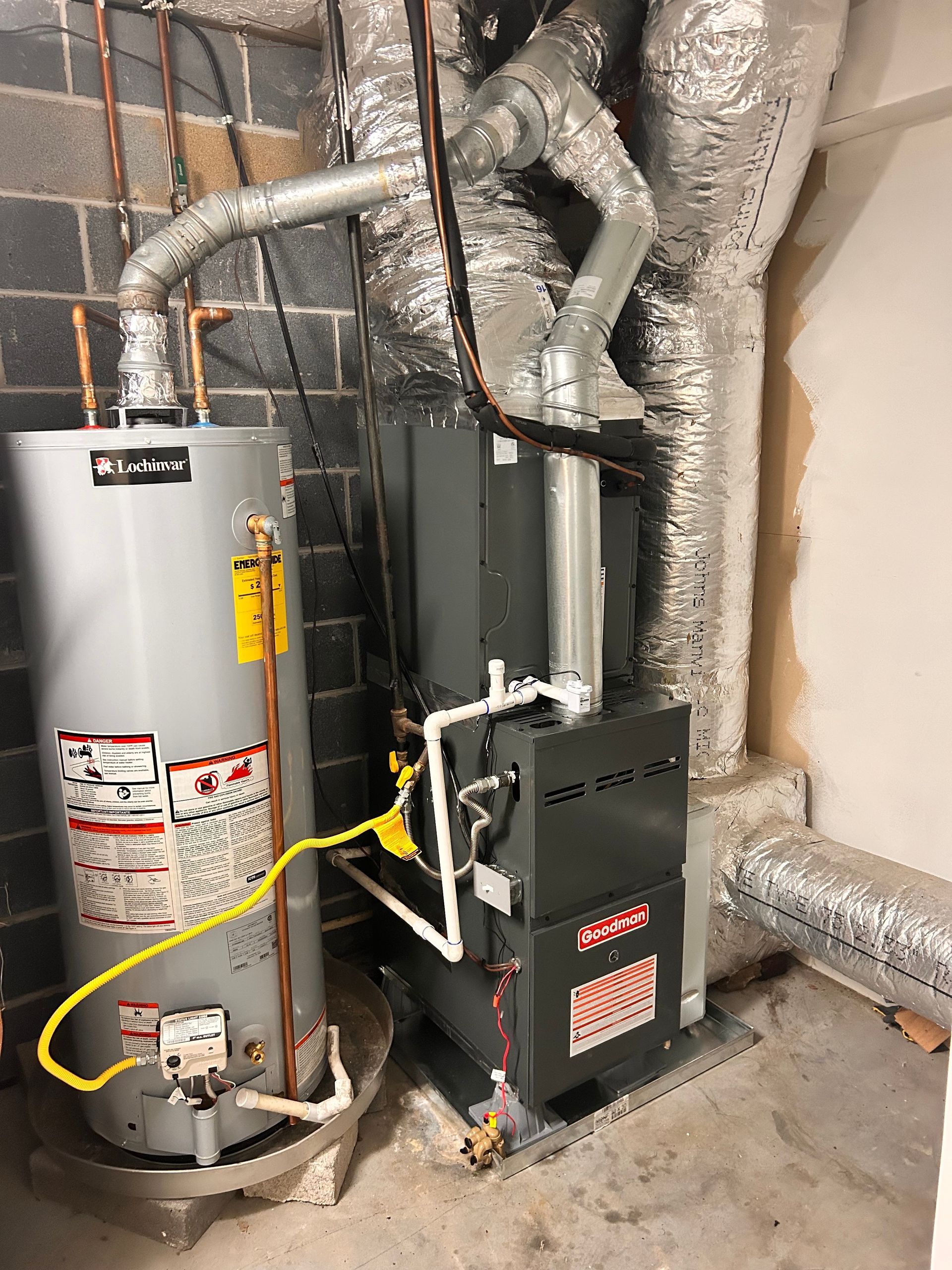 Water heater and furnace in a utility closet with exposed insulated ductwork and pipes