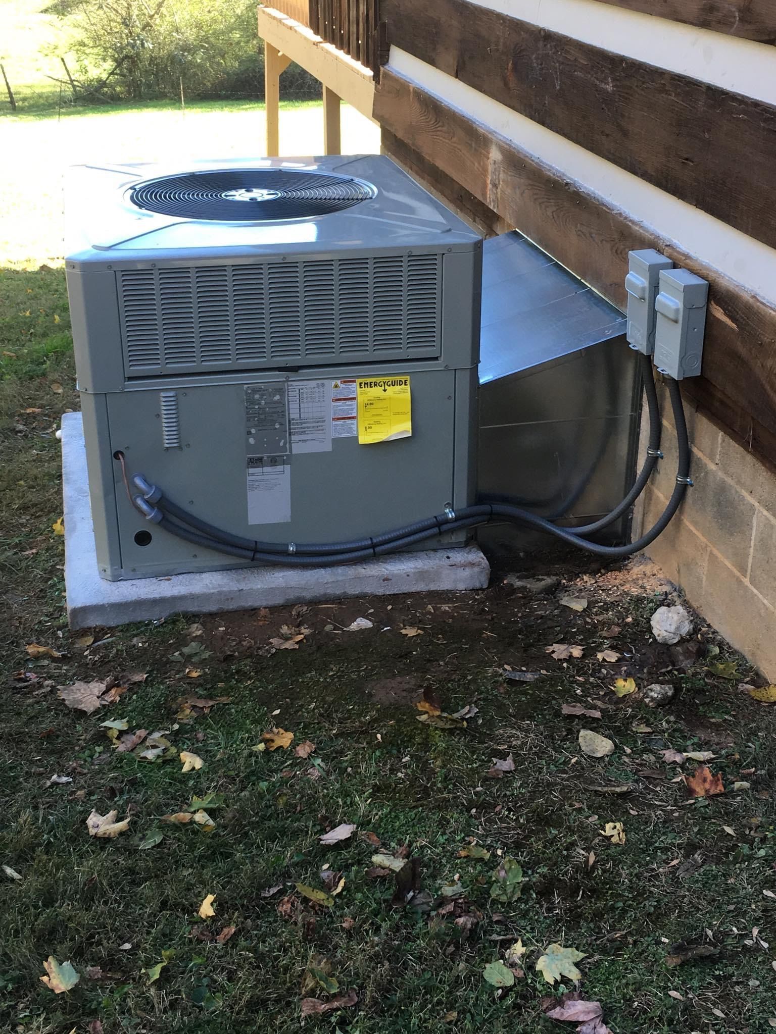 Outdoor HVAC unit beside a house wall, with hoses and electrical conduit attached.
