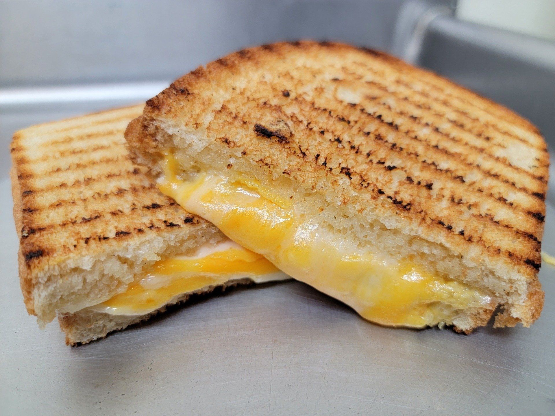A grilled cheese sandwich sliced in half, showing melted yellow cheese between two pieces of toasted, grill-marked bread.