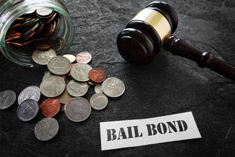 A jar of coins next to a judge 's gavel and a sign that says bail bond. A jar of coins next to a judge 's gavel and a sign that says bail bond.