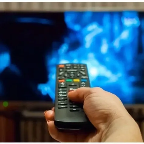 Técnico reparando un televisor en un centro de servicio, con herramientas sobre un banco de trabajo y taquillas al fondo.