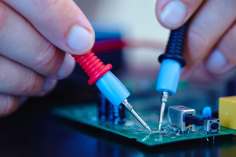 Técnico reparando una computadora de escritorio en un centro de reparaciones con letrero “Central de Reparaciones”