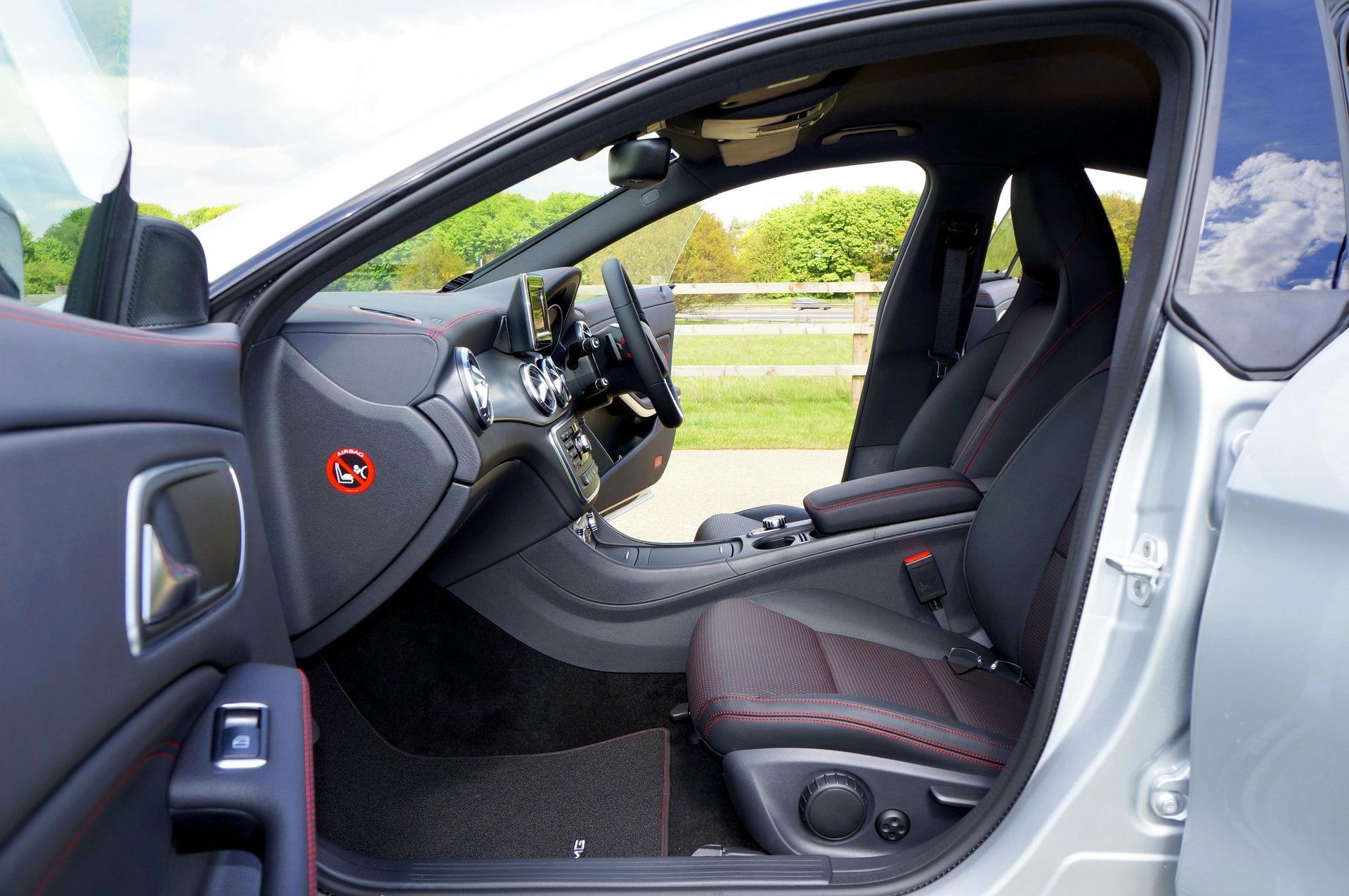 Car interior with open driver door, showing steering wheel, dashboard, and front seats.