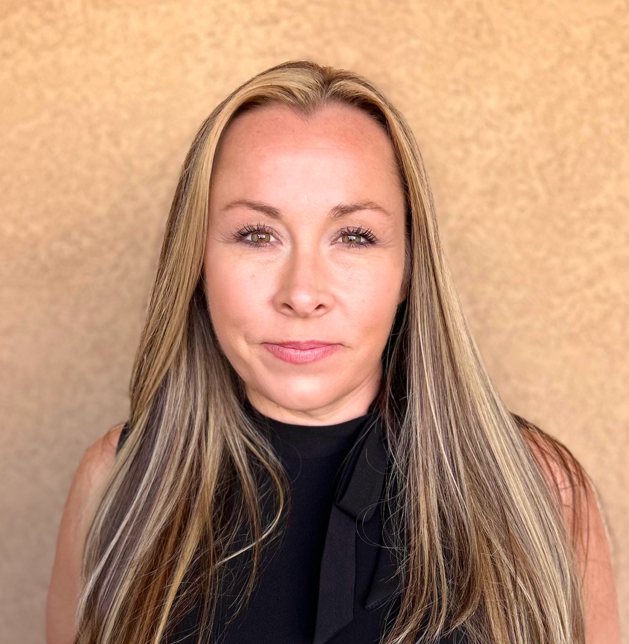 A woman with long blonde hair is wearing a black shirt