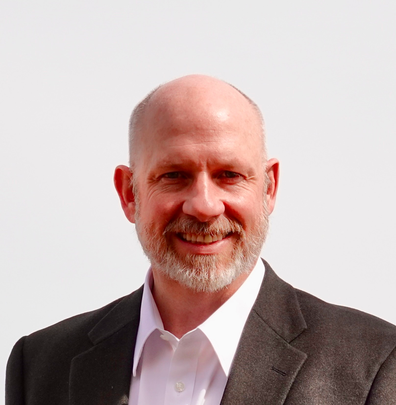 A bald man with a beard wearing a suit and white shirt