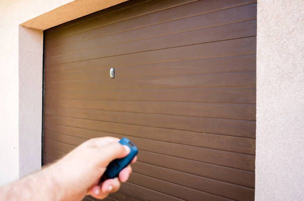 Hand uses remote controller for closing and opening garage door.