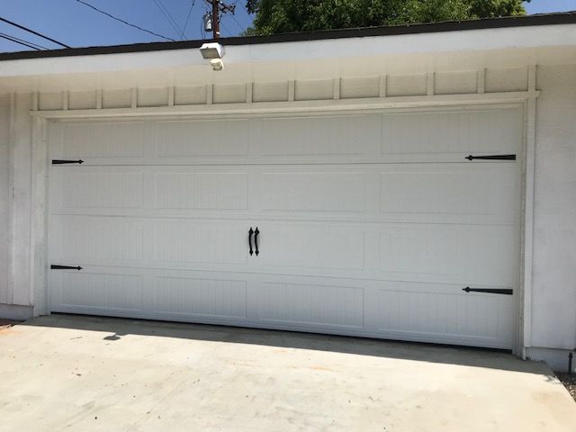 White garage door with black hardware, set in a concrete driveway.
