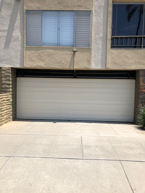 Tan garage door in a building facade with a concrete driveway.