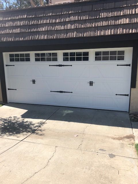 White garage door with decorative black hardware and small windows.