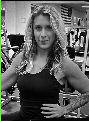 A woman is standing in a gym with her hands on her hips.