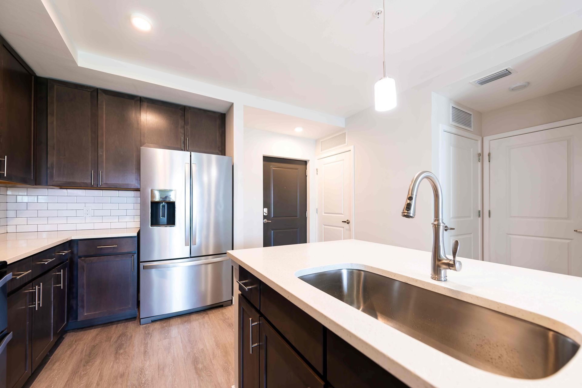 Modern kitchen with stainless steel appliances, dark cabinets, and a white island with a sink.