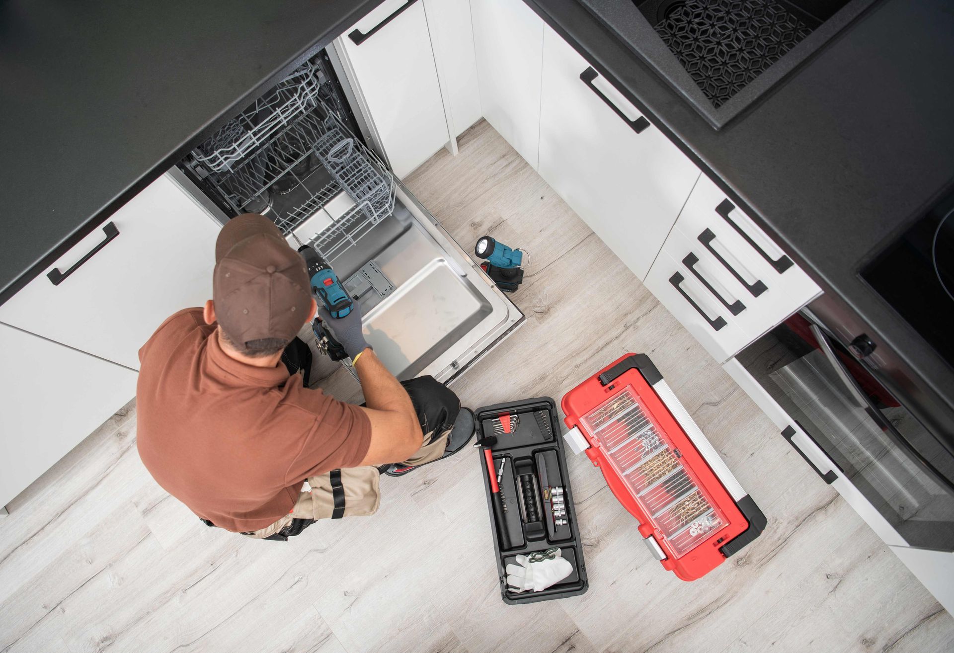 Technician kneels beside open server cabinet, using a tool kit in a data center.