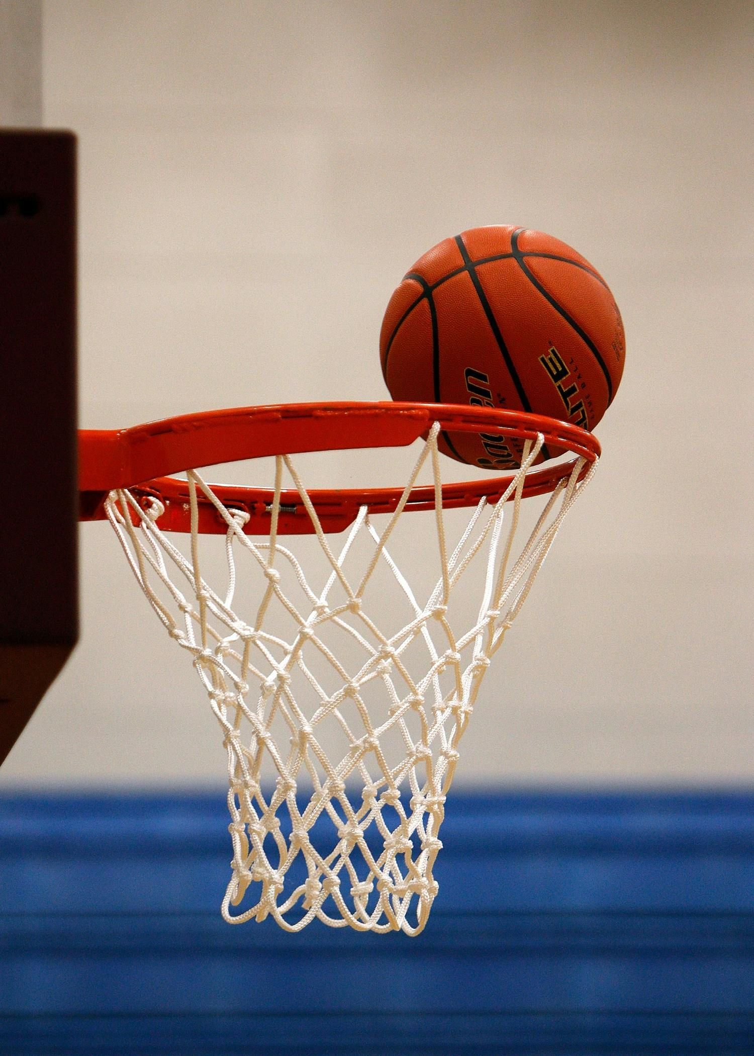 Basketball about to go through a hoop.