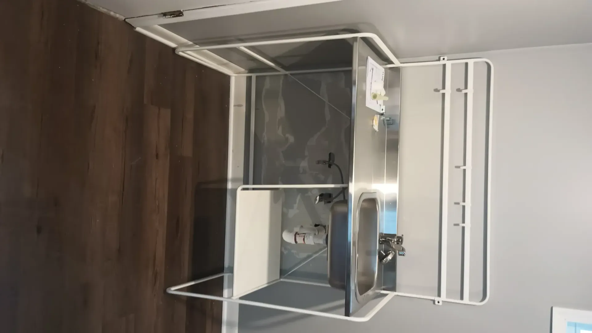Empty room with wood floor, mirrored wall, and a metal clothing rack or shelving unit.