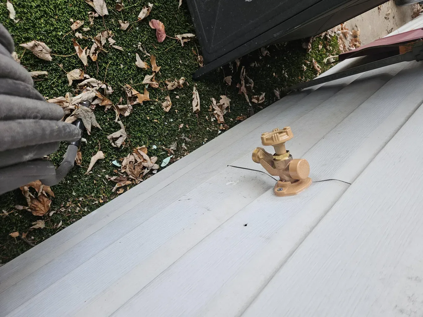 Small tan figurine on a white ledge beside grass and fallen leaves