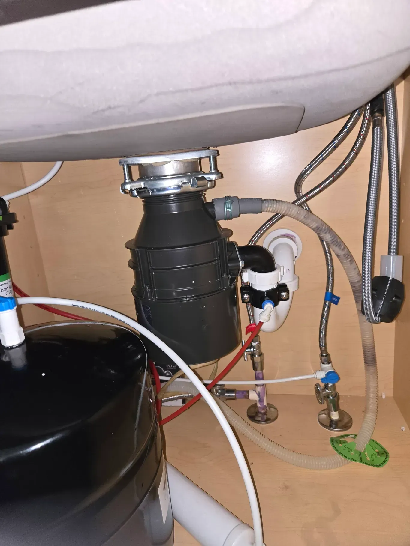Under-sink plumbing with garbage disposal, drain pipes, and water shutoff valves in a cabinet