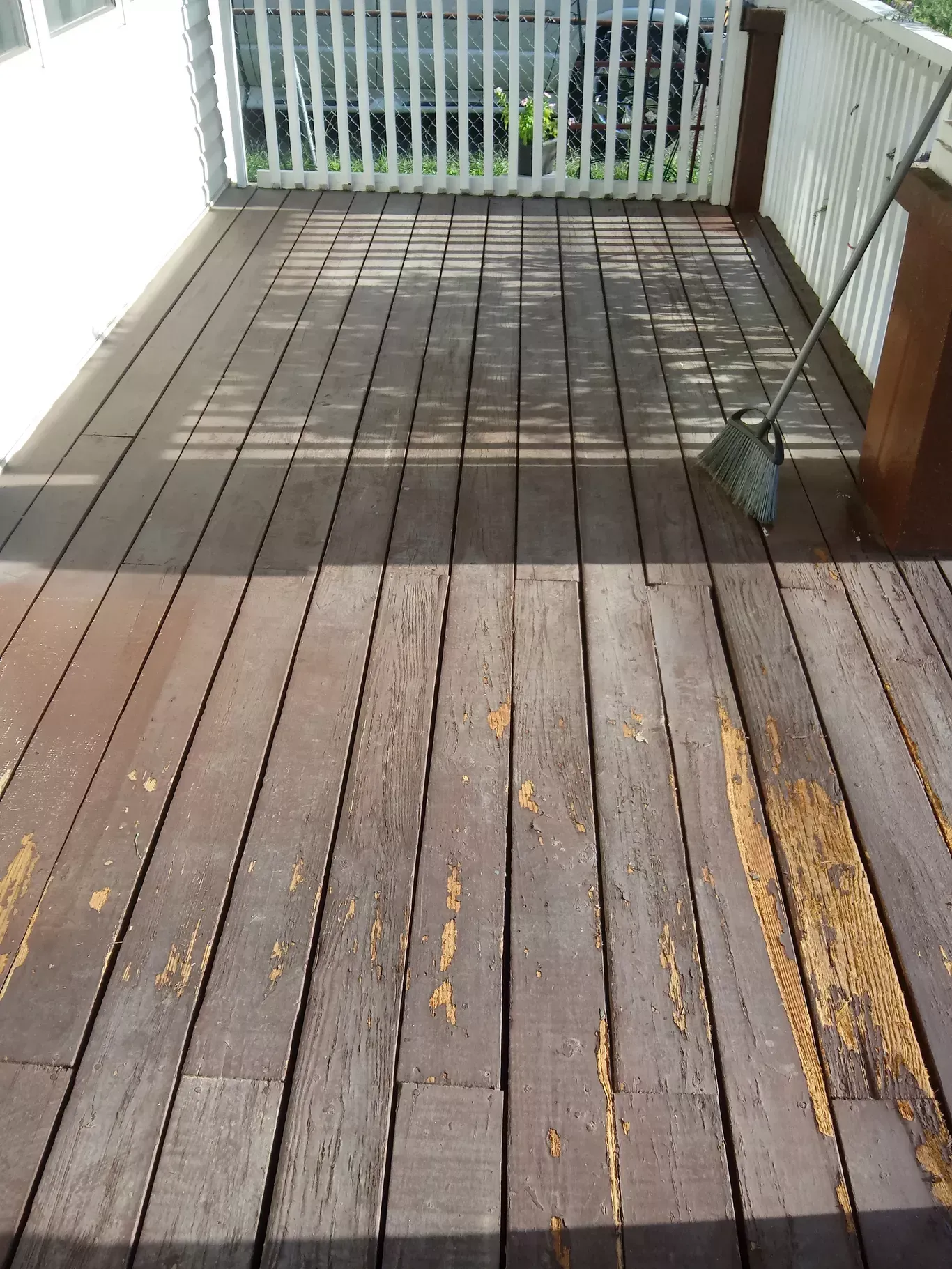 Wooden deck with weathered boards, metal railing, and a small plant in a corner.