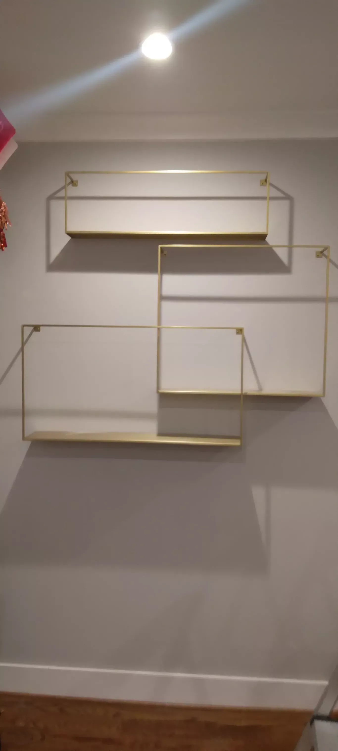 White geometric wall shelf set mounted on a light gray wall above a baseboard.
