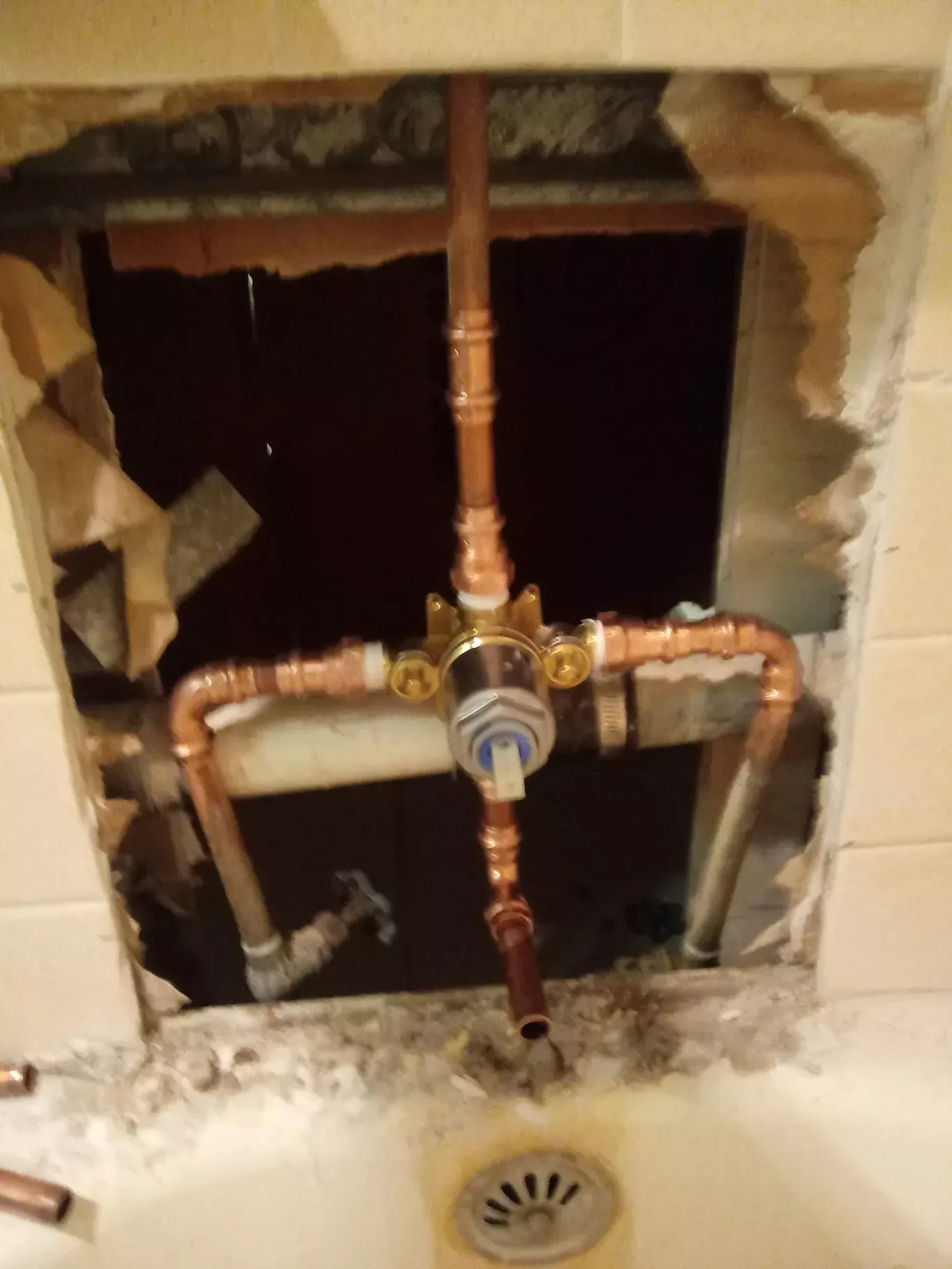 Exposed copper plumbing in a wall opening above a sink drain