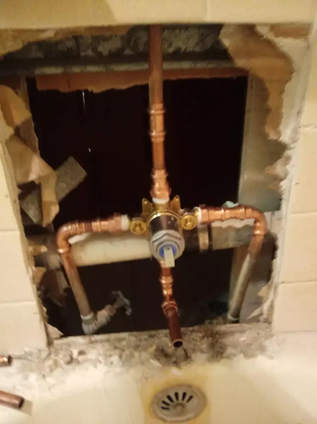 Exposed copper plumbing in a wall opening above a sink drain
