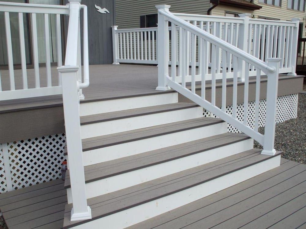 White railing and steps lead up to a deck with gray decking boards.