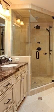 Bathroom with a glass shower enclosure and a vanity with a dark countertop and off-white cabinets.