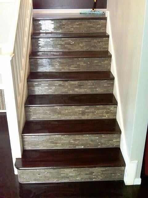 Staircase with dark wood treads and stone-like tile risers, flanked by white banister and wall.