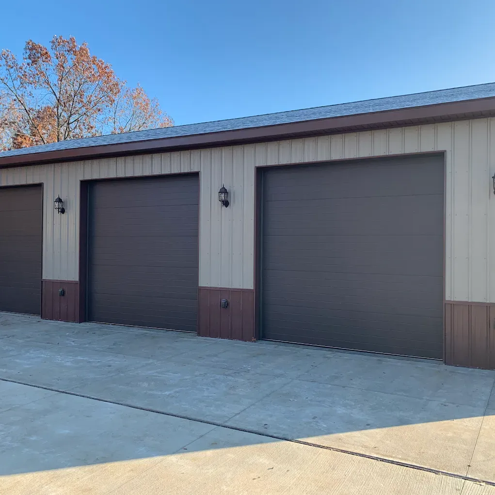 Three garage doors, brown and tan, set against a blue sky.