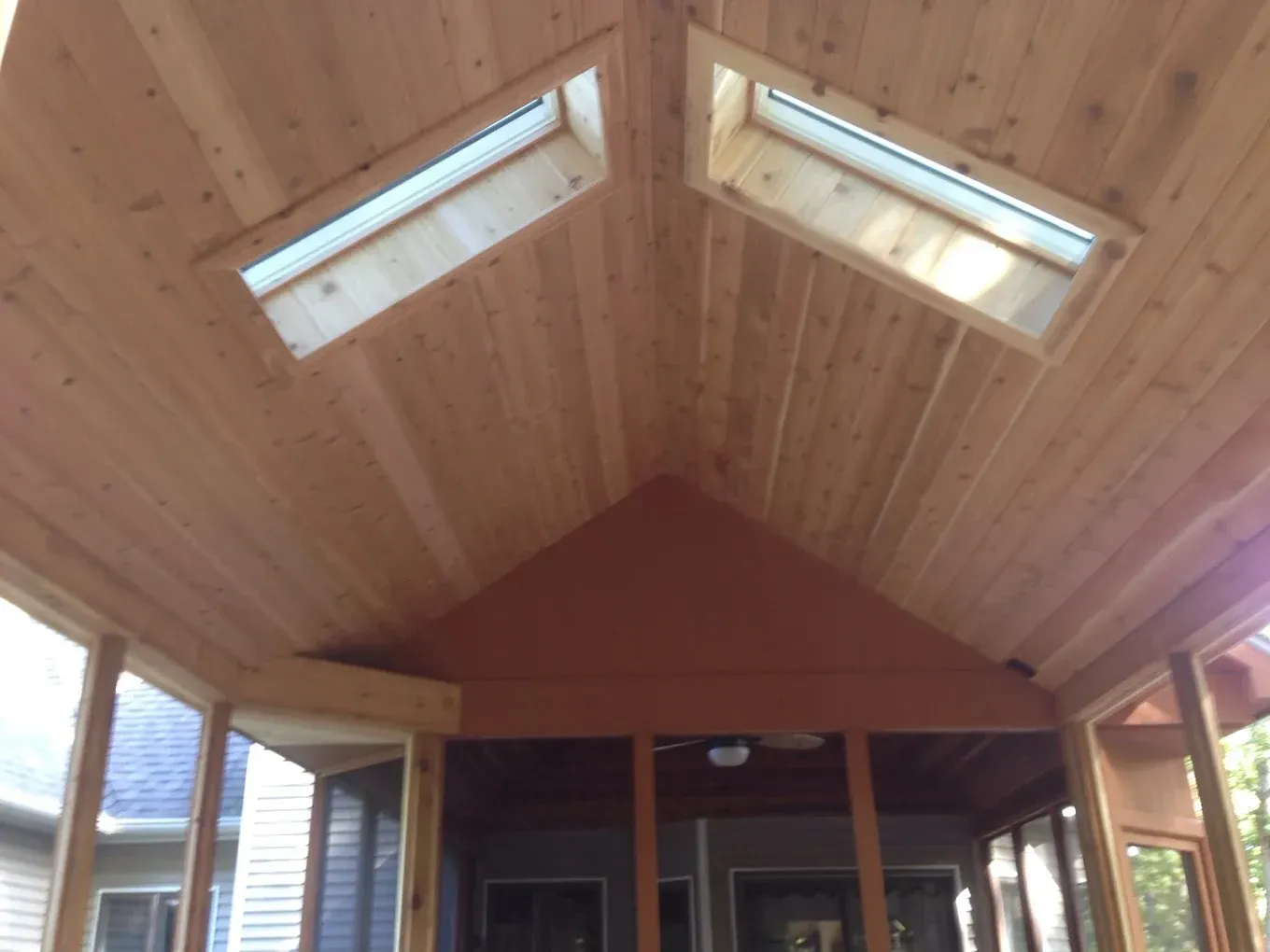 Screened porch ceiling with cedar planks and two skylights.