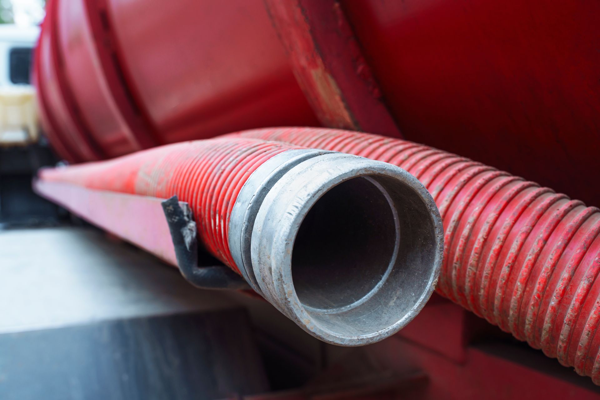 Red corrugated hose with silver end, mounted on a red tank.