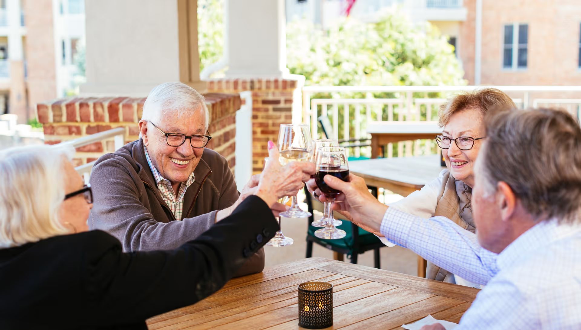 A group of older people are sitting at a table toasting with wine glasses.