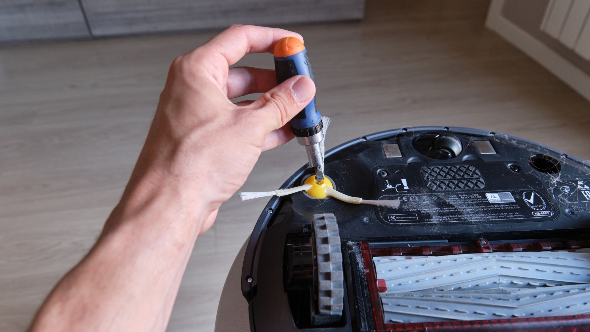 Hand using a screwdriver to tighten a small yellow fastener on a black device body.