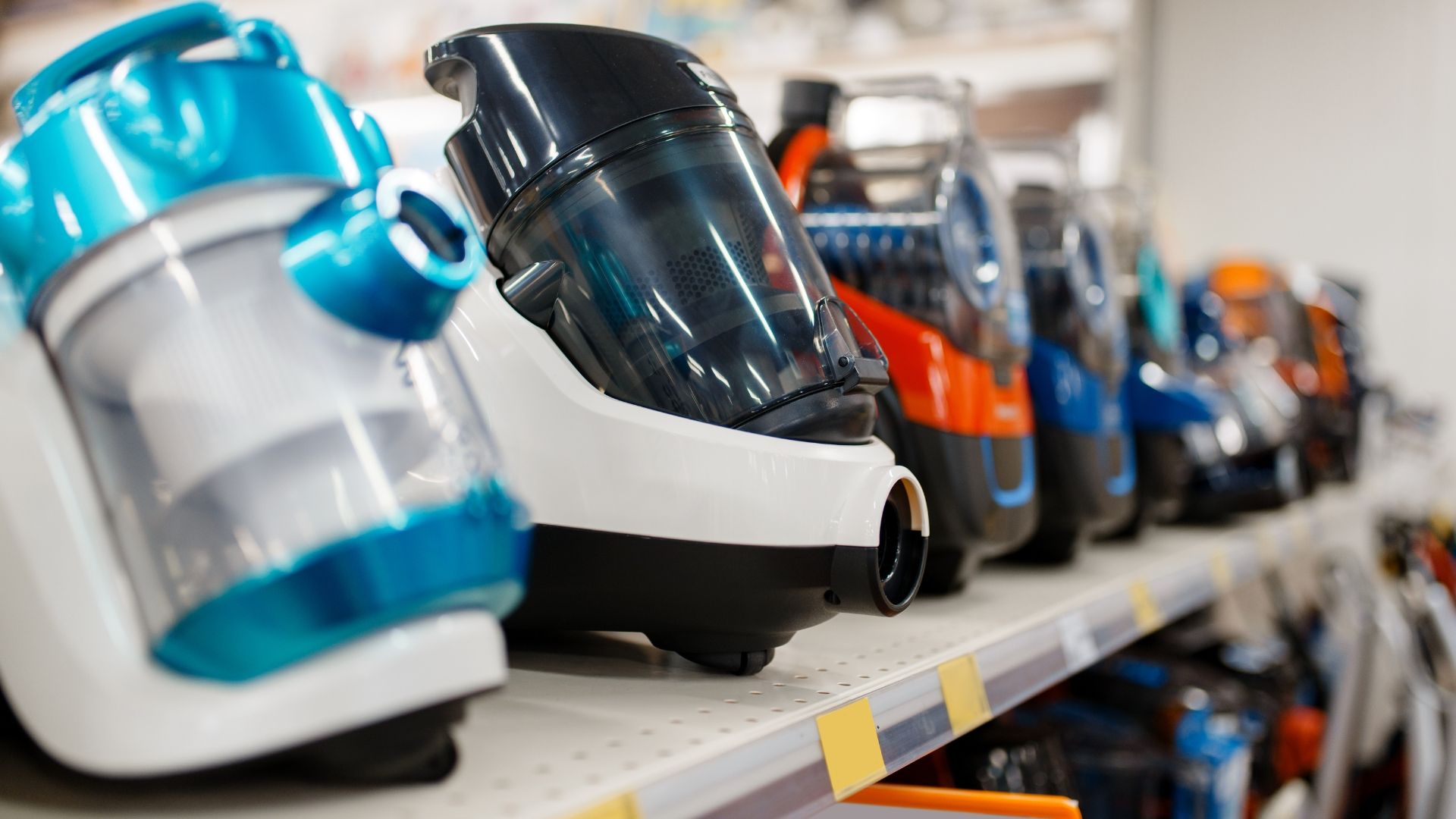 Row of colorful vacuum cleaners displayed on a store shelf