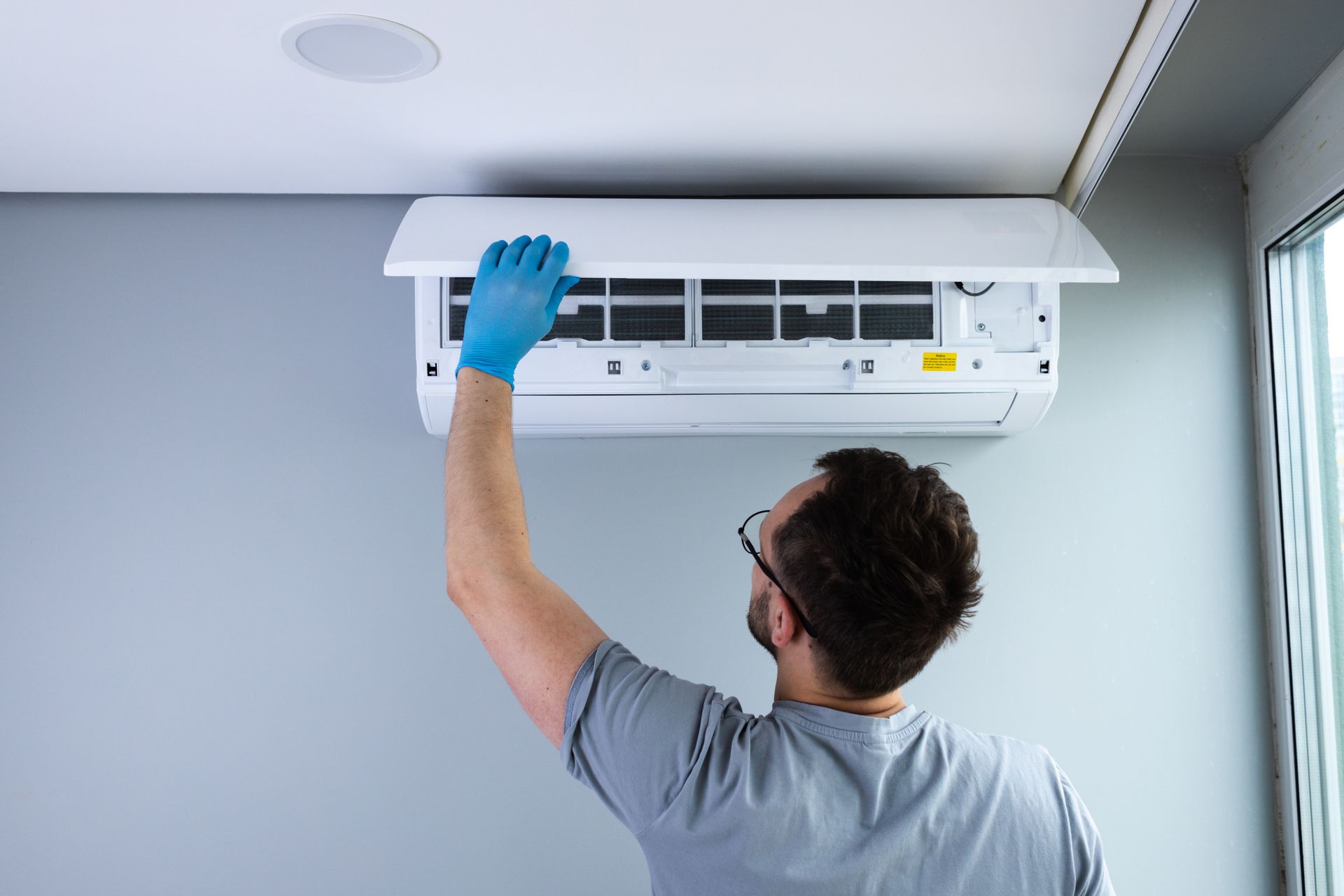 Technician installing a wall-mounted AC unit.