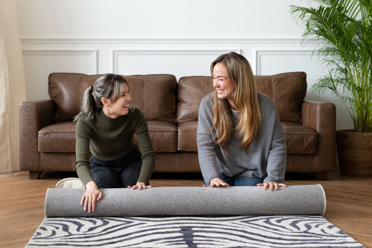 Two women are sitting on the floor looking at a rug.