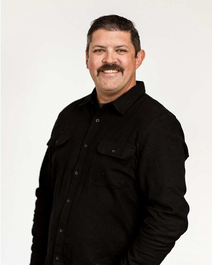 Man in a black shirt smiling against a light background
