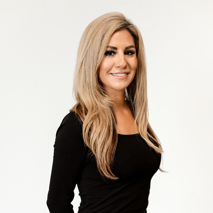 A woman with long blonde hair is wearing a black shirt and smiling.