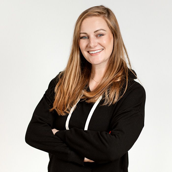 Smiling person in a black hoodie with arms crossed against a white background