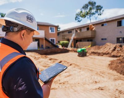 Construction worker in hard hat and vest taking notes at a residential building site