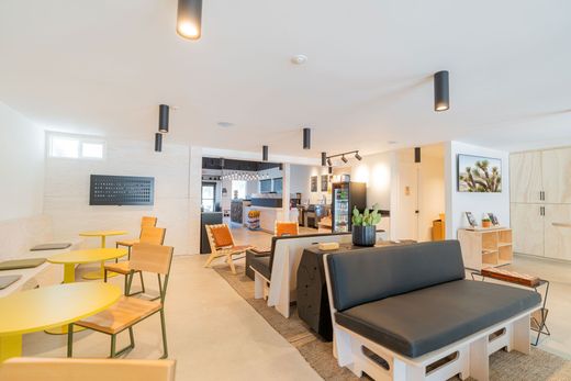 Bright modern café with yellow tables, sofas, and a central counter in an open seating area