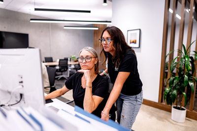 Two coworkers reviewing a computer screen in a modern office
