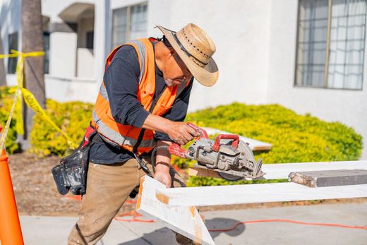 Construction worker cutting wood on a sawhorse outdoors with a circular saw