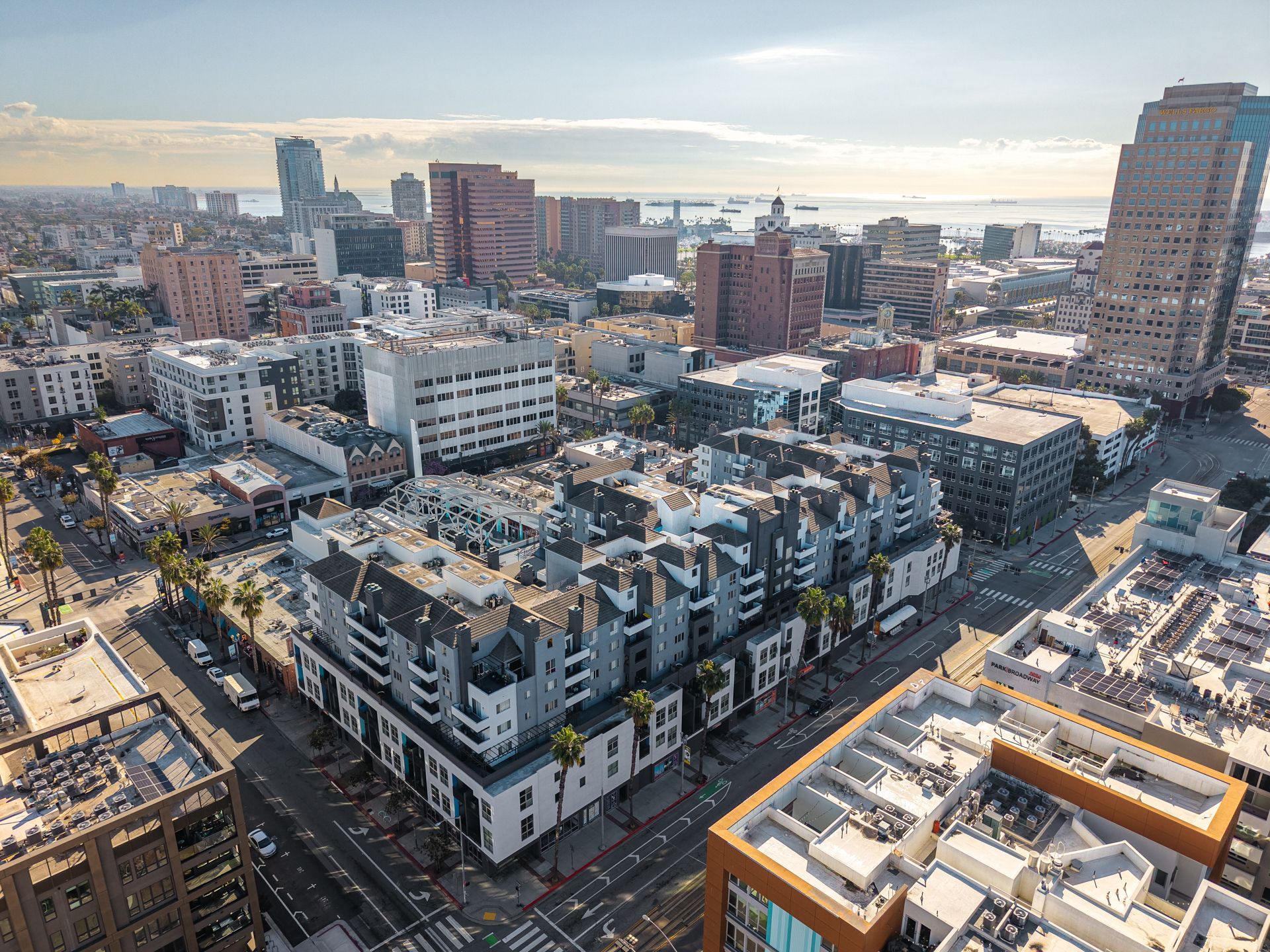 Aerial view of a city skyline with apartment buildings, streets, and sunlight reflecting off distant water