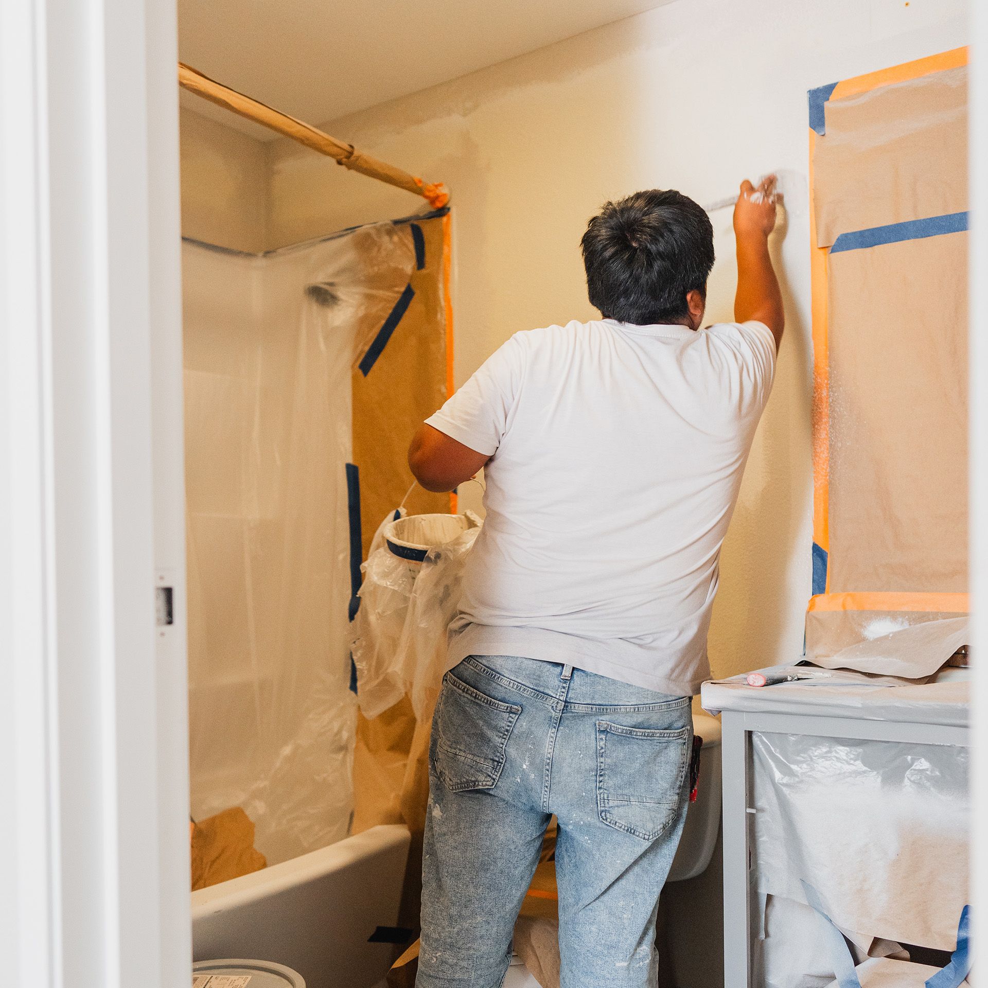 A man is painting a wall in a bathroom