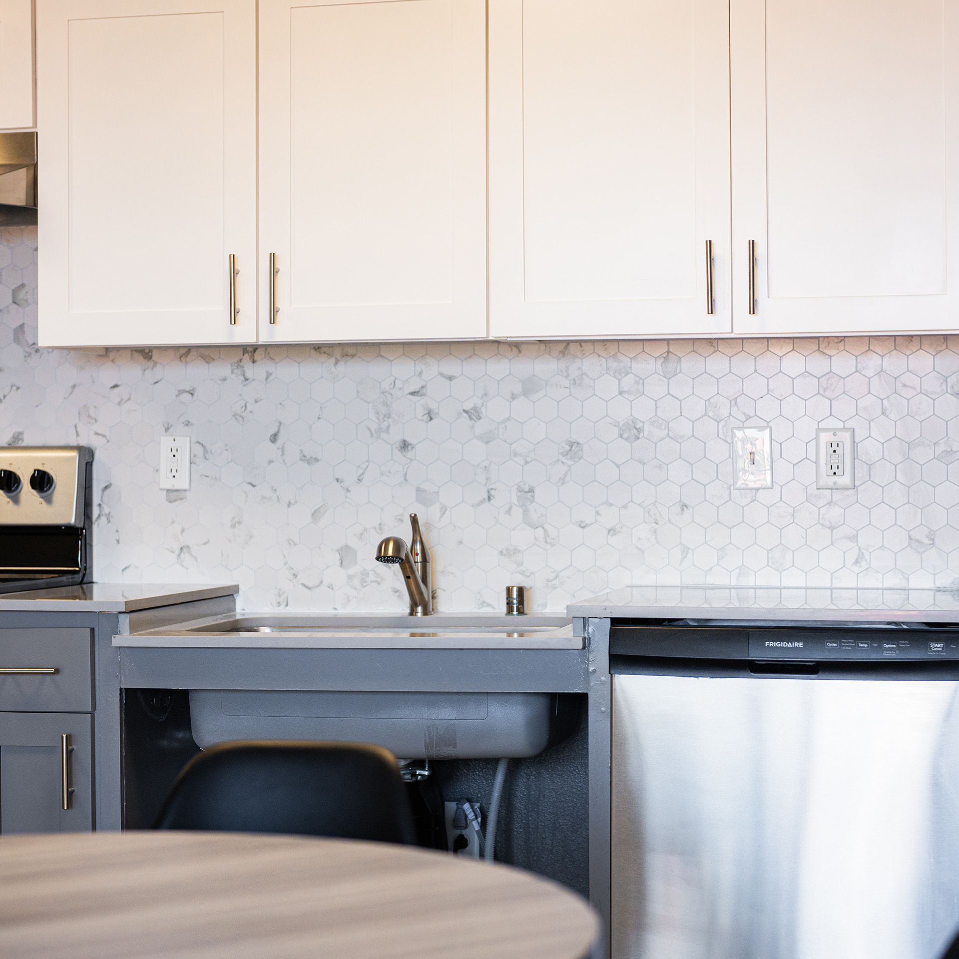 A kitchen with white cabinets and a stainless steel dishwasher
