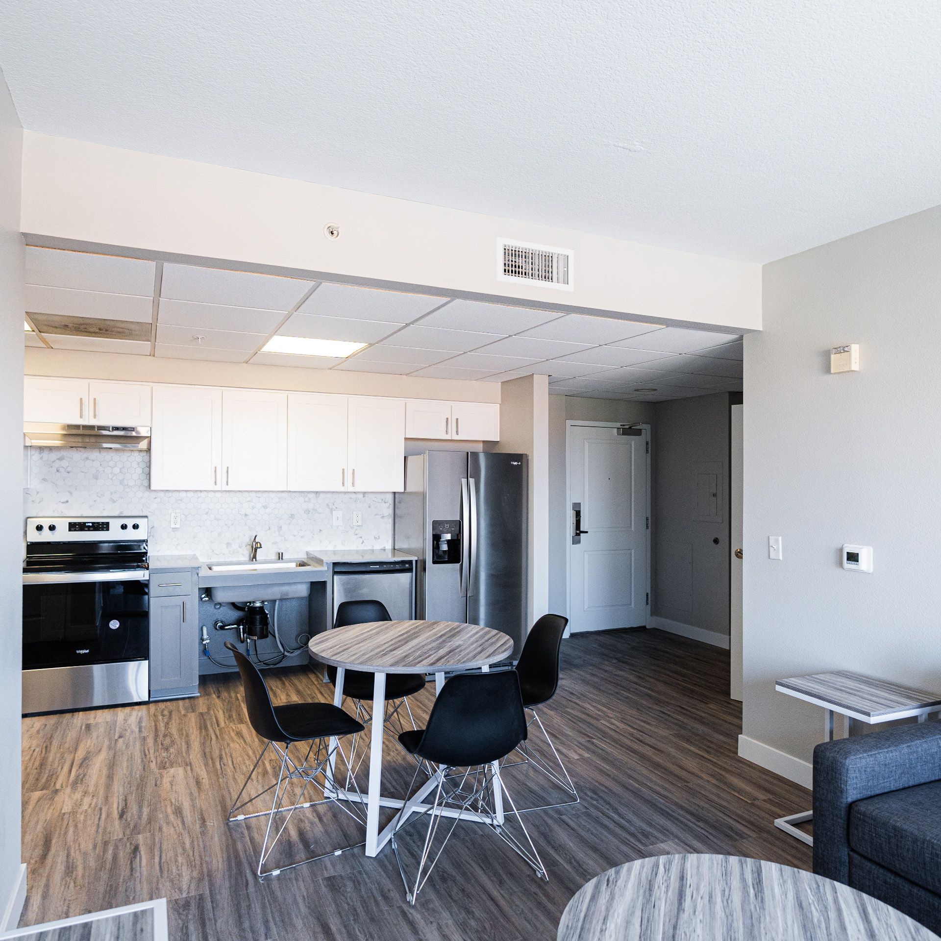 Modern kitchen and dining area with stainless-steel appliances, wood floors, and a round table with black chairs